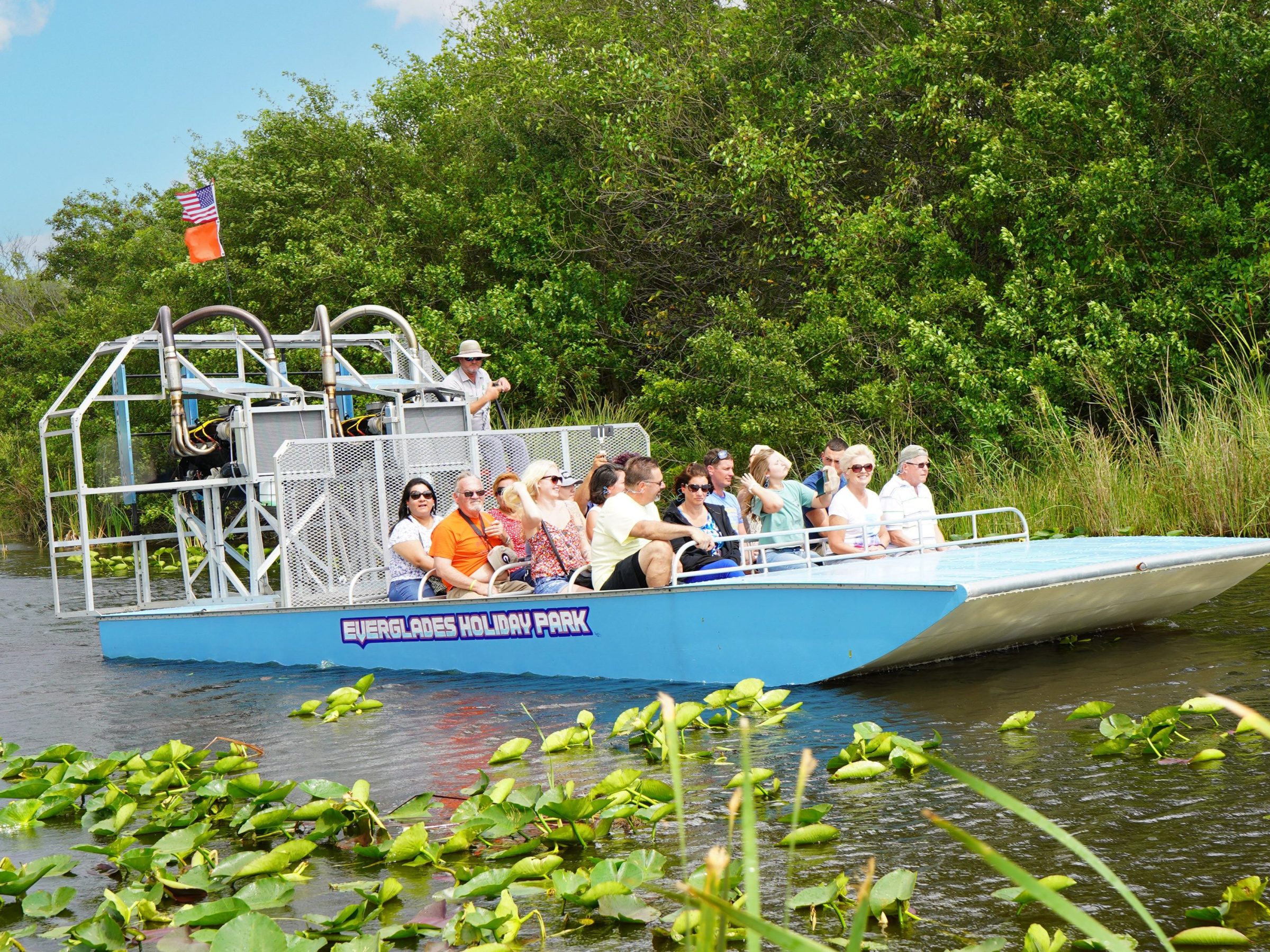 Group of tourists on an airboat tour in a swamp with lush vegetation.