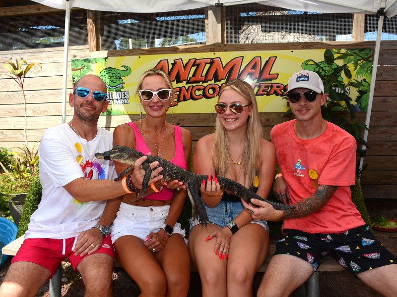 Four people holding an alligator at an animal encounter event.